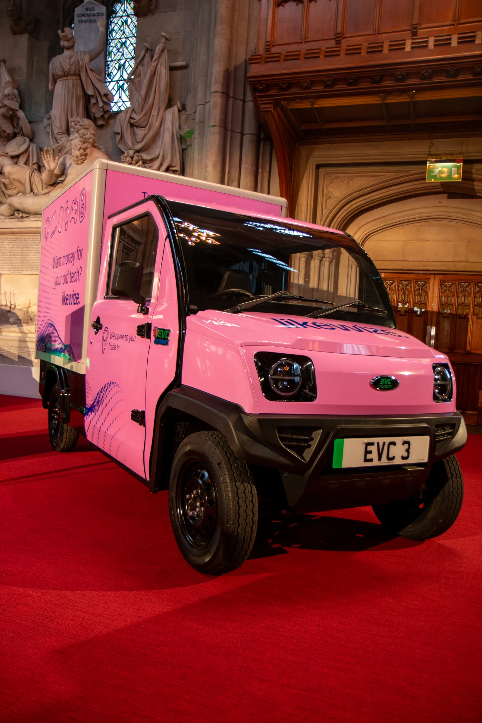 A pink EVC electric van stands on a red carpet beneath the carved stone and wood of London's Guildhall.