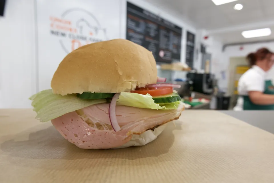 A freshly made filled roll on the counter at Ginger Butchers' deli, with the menu boards behind